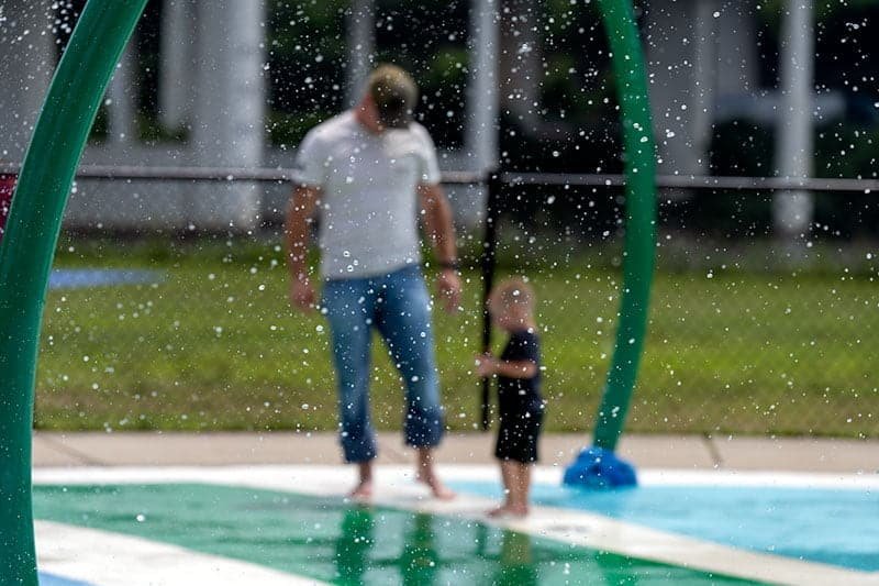 Family Fun at Charleston Water Park - Candid Moments Child and parent enjoying water sprinkles at a park in Charleston, WV