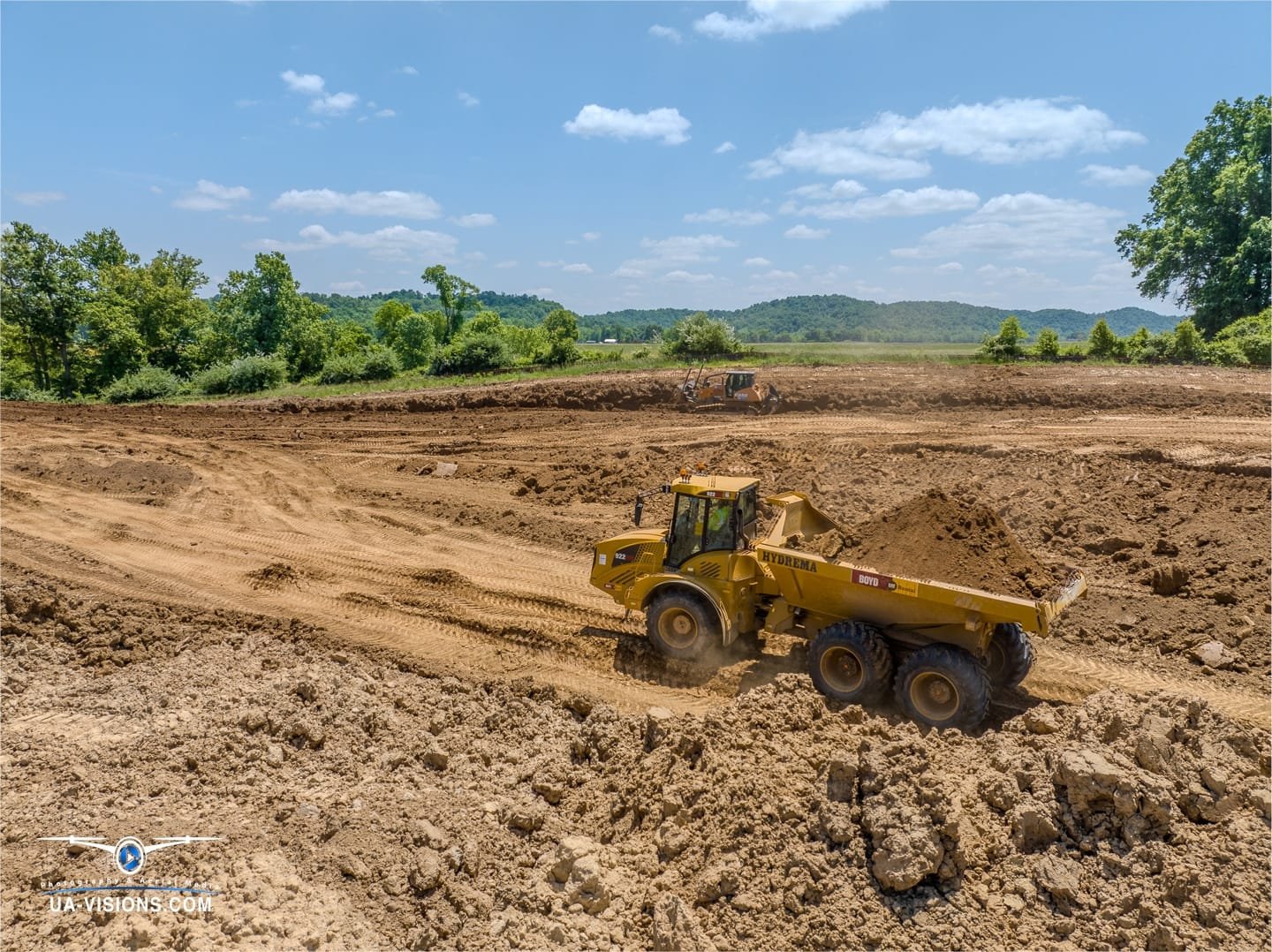 Caught mid-dance by UA-Visions, an articulated dump truck performs a dirt ballet across the evolving stage of SDRS.
