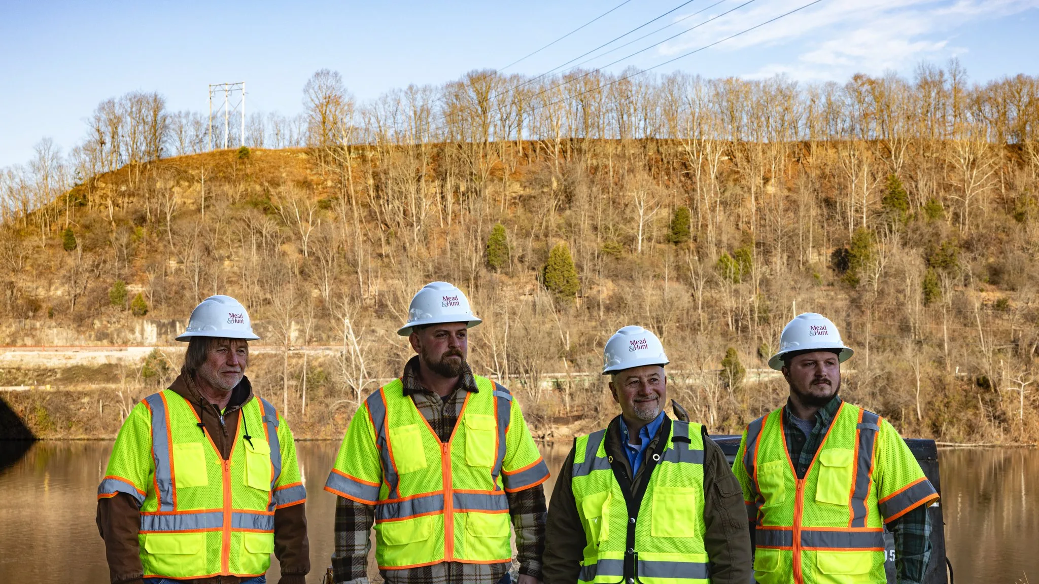 Our Portfolio of Digital Creations Mead and Hunt field team wearing hard hats and high-visibility jackets beside the bridge