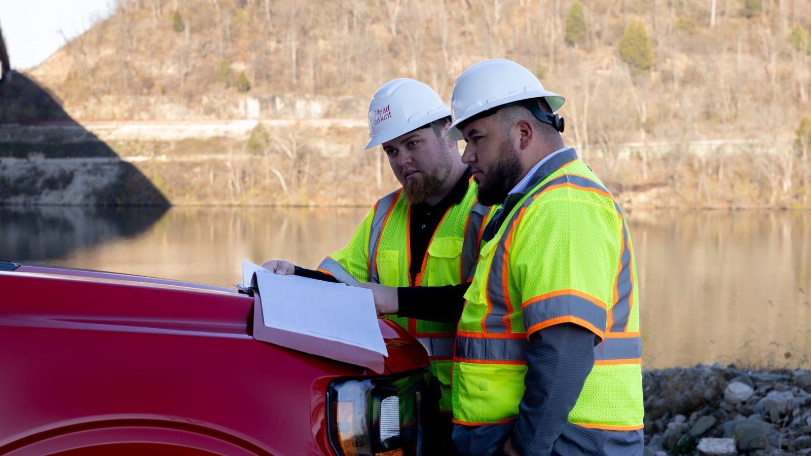 Mead & Hunt Team and Project Photography Two field team members reviewing drawings beside a red pickup truck