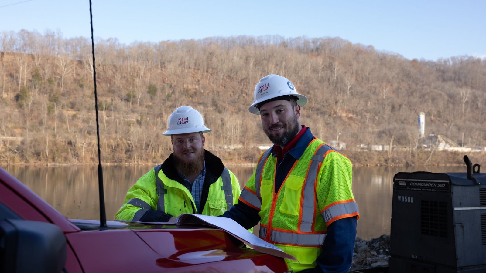 Mead & Hunt Team and Project Photography Team members discussing project drawings beneath the bridge