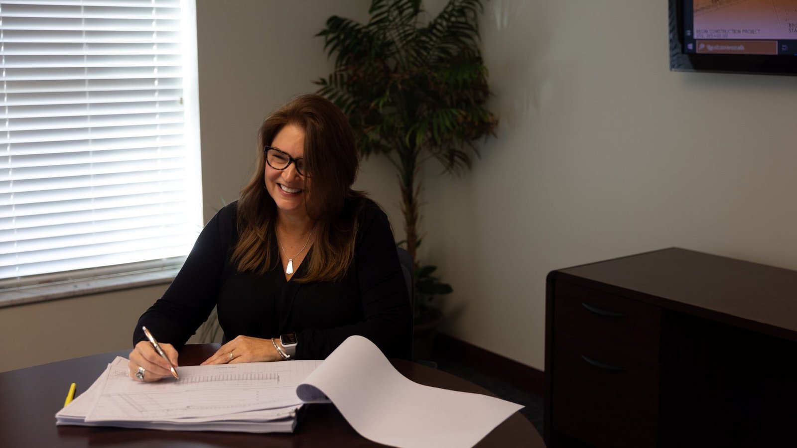 Mead & Hunt Team and Project Photography Office portrait of a team member reviewing paperwork at a desk