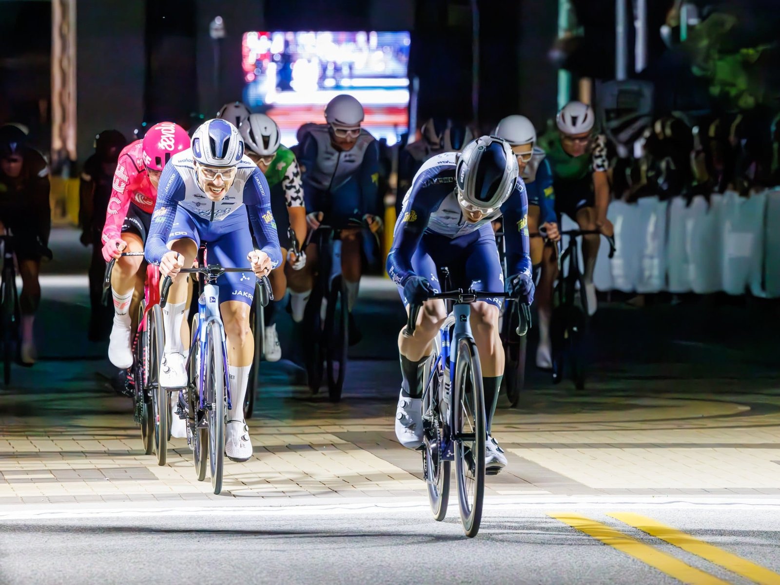 USA Cycling 2025 Photography and Video Riders approaching under street lights during evening criterium coverage